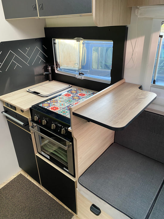 Made to measure flip up shelf in oak laminate with black edging, flipped up beside the hob in a motorhome kitchen